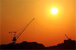 Construction cranes silhouettes at sunset