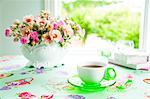 Cup of coffee and rose bouquet on a table