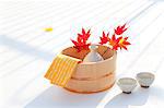 Towel, sake bottle and red maple leaves in a wooden basket