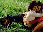 Women Hugging, Man Lying in Grass
