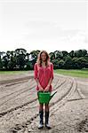 Young woman with watering can on field