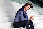 Businesswoman on stairs looking at cell phone