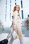 Businesswoman walking with trolley suitcase on pavement