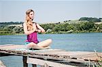 Blonde junge Frau praktizieren Yoga am See