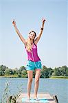 Blond young woman listening to music at a lake