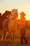 Young woman with horse on meadow in backlight