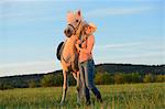 Femme souriante à cheval sur la prairie