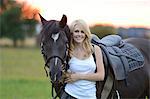 Femme souriante à cheval sur la prairie