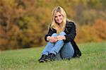 Smiling blond young woman sitting in autumnal meadow