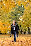 Man carrying woman piggyback in autumnal landscape