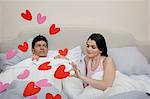 Couple in bed with heart shapes on bedclothes