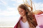 Girl by the sea wearing a towel, wind in her hair