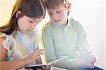 Girl and boy using digital tablet with bright light