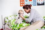 Mother holding cell phone to sons ear in bed