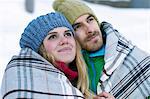 Portrait of couple wearing knit hats, wrapped in blanket