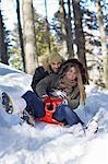 Couple tobogganing in snow