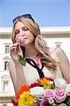 Young woman smelling rose from bouquet of flowers, eyes closed