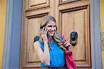 Young woman using cellphone near doors