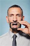 Man with smartphone over mouth