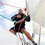 Man on yacht, pulling ropes