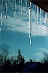 Icicles under roof eaves against winter sky