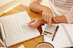 Woman using calculator with laptop