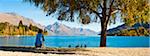 Panorama of a tourist relaxing by Lake Wakatipu in autumn at Queenstown, Otago, South Island, New Zealand, Pacific