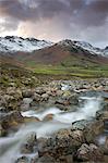 Rivière Redacre Gill tumbling sur les rochers vers la neige capped montagnes qui entourent la Great Langdale, Parc National de Lake District, Cumbria, Angleterre, Royaume-Uni, Europe