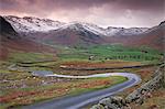 Petite route sinueuse qui mène à la vallée de Langdale, entourée de montagnes recouvert de neige, Parc National de Lake District, Cumbria, Angleterre, Royaume-Uni, Europe