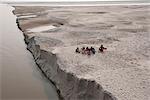 Villagers stopping to eat near the fragile edge of a sandspit in the River Ganges, Sonepur, Bihar, India, Asia