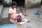 Frau Spinnen Seide von hand außerhalb ihres Hauses, Vaidyanathpur, Orissa, Indien, Asien