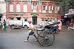 Running rickshaw wallah outside beautiful old Raj era Kolkata building in Kolkata backstreet, West Bengal, India, Asia