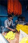 Mala maker (garland maker) at work with orange and yellow marigolds in morning flower market, Howrah, Kolkata, West Bengal, India, Asia