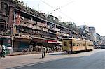 Yellow Kolkata tram passing Kolkata slums in the early morning, Kolkata, West Bengal, India, Asia