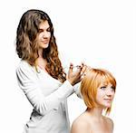 Young nice woman hairdresser makes hairstyle for a girl isolated on white background