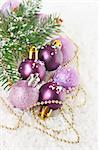 Christmas decoration with pink and lilac baubles on the snow.