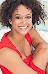 A beautiful mixed race African American girl or young woman lwearing a red dress looking happy and smiling
