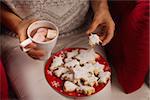 Closeup on woman eating Christmas cookie and drinking hot chocolate with marshmallows