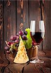 Wine glass and cheese in a basket on a wooden background