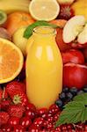 Orange juice in a bottle surrounded by fresh fruits