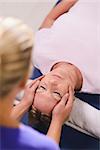 Alternative traditional medicine and massage, young spirit healer doing reiki treatment to old woman. Head and shoulders