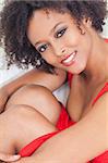 A beautiful mixed race African American girl or young woman wearing a red dress looking happy and smiling