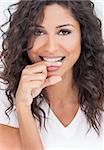 Studio portrait of a beautiful young mixed race Latina Hispanic woman smiling and biting her finger with perfect teeth