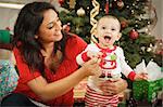 Young Attractive Ethnic Woman With Her Newborn Baby Near The Christmas Tree.