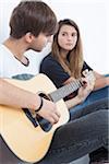 Young Man Playing Acoustic Guitar to Teenage Girl