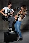 Young Man and Teenage Girl Playing Electric Guitars
