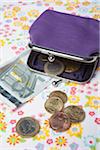 Purple Change Purse with European Coins and Paper Currency on Patterned Background