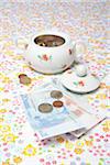 Sugar Bowl Filled with Euro Coins and Paper Money on Table