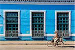 Man Riding Bicycle Past Bright Blue Building, Trinidad, Cuba