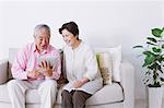 Senior adult couple sitting on a sofa with electronic tablet